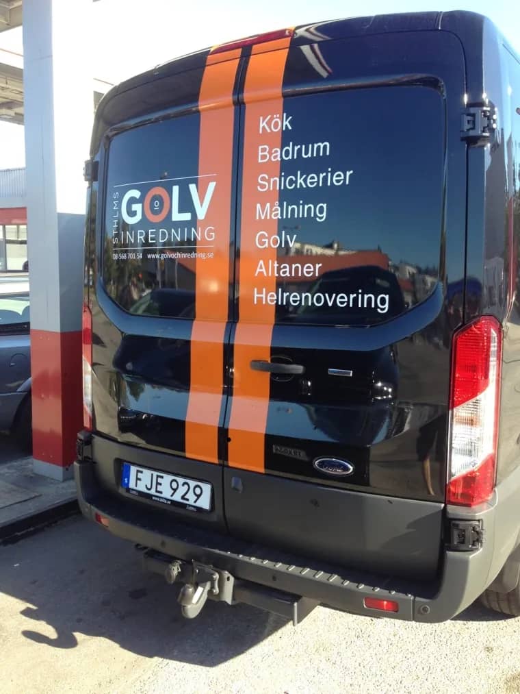 Svart skåpbil med orangea ränder och reklam för "Golv inredning". Registreringsnummer FJE 929